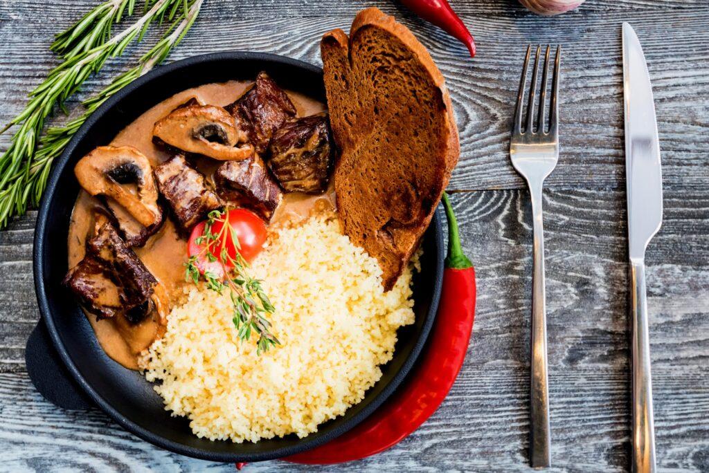 Top view mushroom beef stroganoff in frying pan with couscous