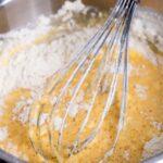 Bowl of batter and whisk on wooden table