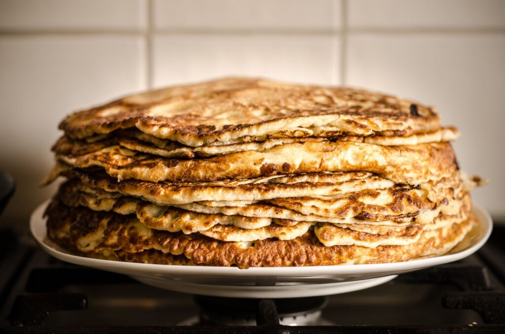 Une délicieuse pile de crêpes maison sur une assiette blanche, parfaite pour le petit déjeuner.