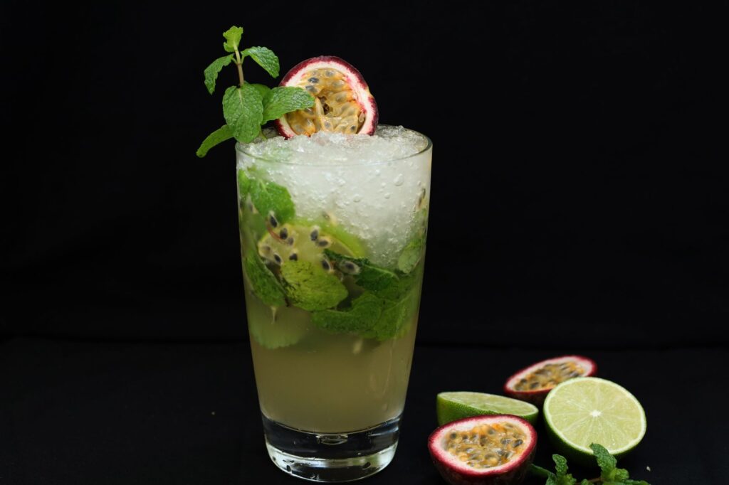Un gros plan d'un mojito rafraîchissant à la passion, garni de menthe et de citron vert, parfait pour une journée d'été.