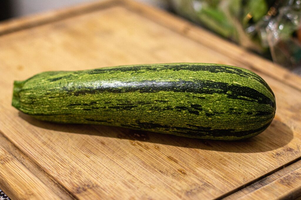 Gros plan d'une courgette sur une planche à découper en bois, idéal pour vos besoins en photographie culinaire.