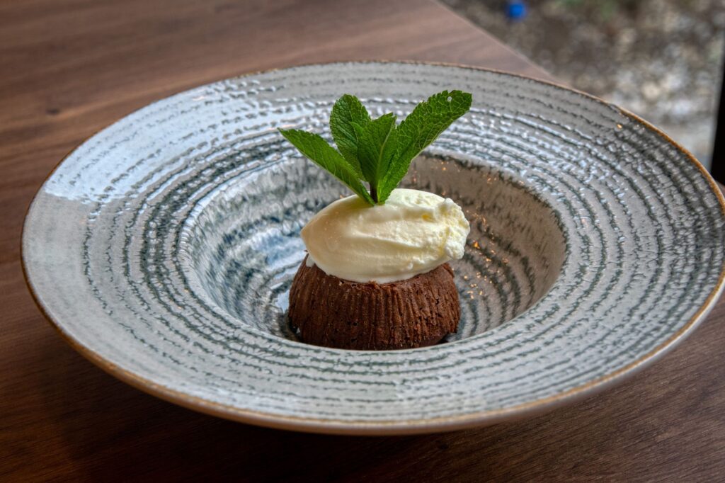 Un délicieux gâteau au chocolat coulant surmonté de glace à la vanille et de menthe, joliment présenté.