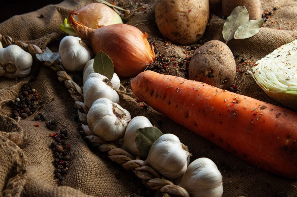 Une variété de légumes frais, comprenant des carottes, de l'ail et des pommes de terre, sur du jute rustique.
