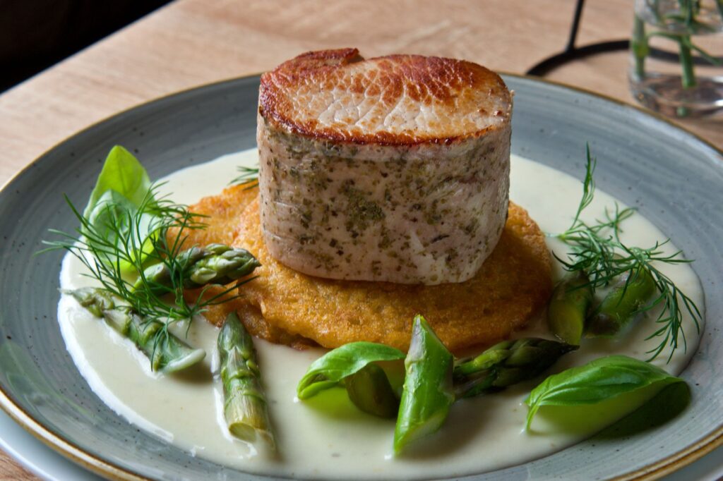 Délicieux plat de porc avec des asperges, des herbes fraîches et une sauce crémeuse aux herbes.