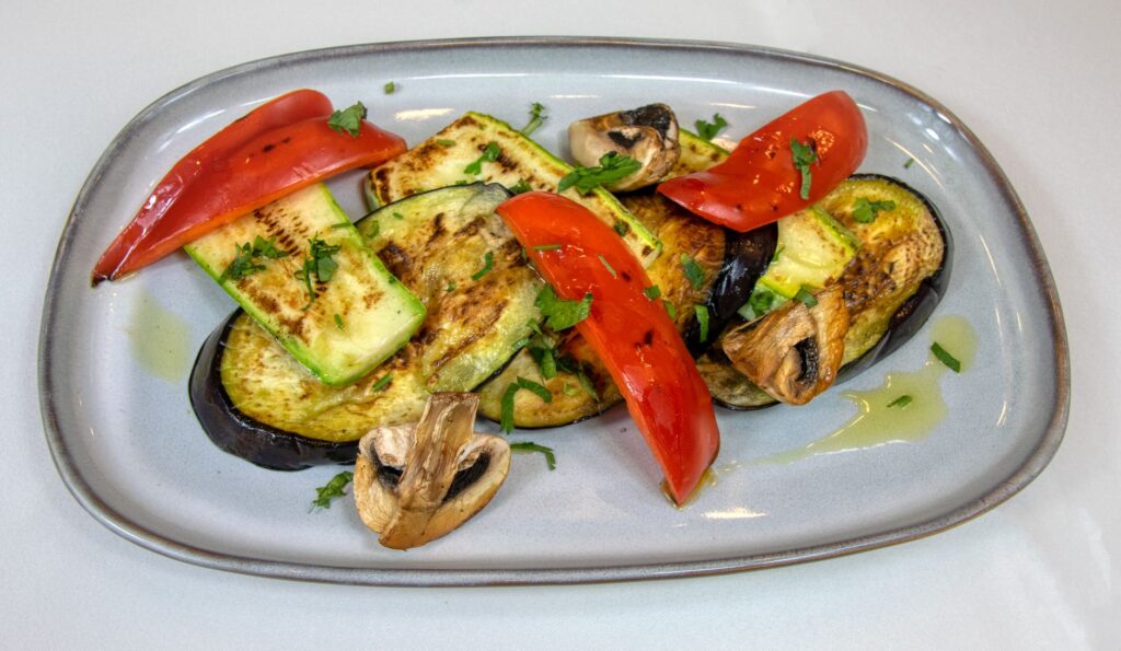 Délicieuse grillade de légumes avec aubergine, courgette et poivrons rouges sur une assiette.