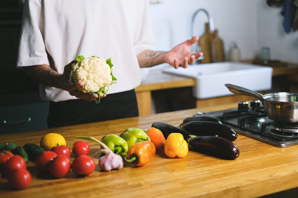 Une variété de légumes frais incluant du chou fleur, des aubergines et des poivrons prêts à être cuisinés sur un plan de travail.