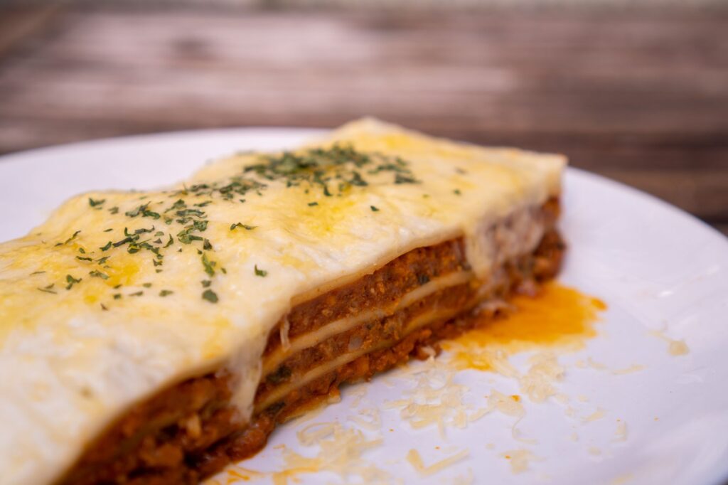 Gros plan d'une part de lasagne maison au fromage sur une assiette, mettant en valeur ses couches et sa garniture.