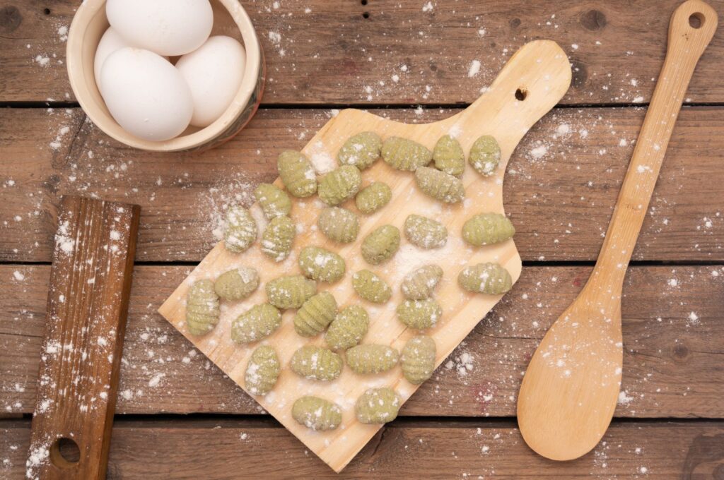 Gnocchi maison frais sur une planche en bois avec de la farine et des œufs.