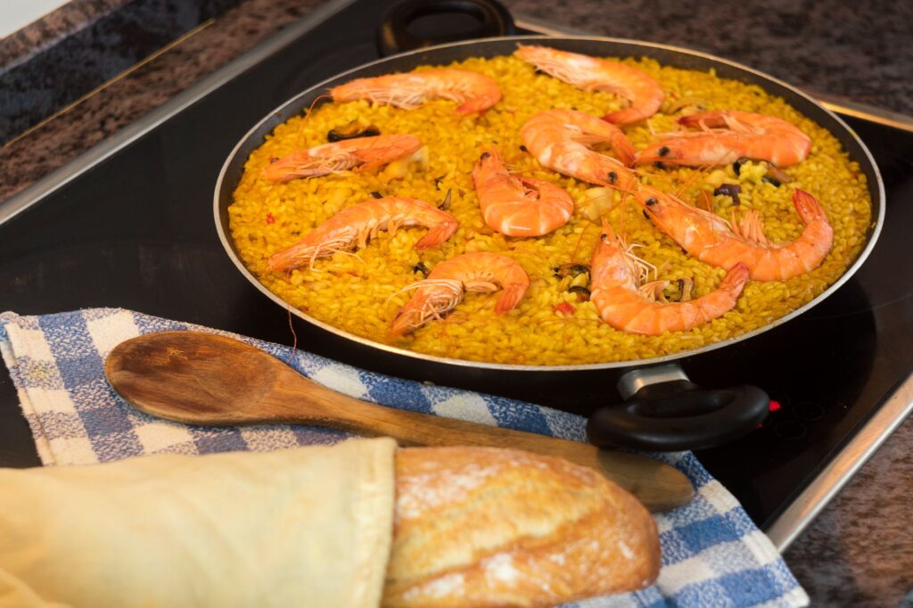 Délicieuse paella de fruits de mer faite maison avec des crevettes, cuite sur une plaque de cuisson, prête à être servie.
