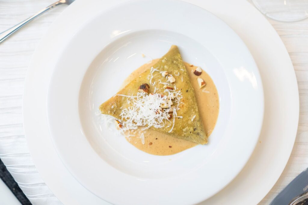 Vue de dessus d'un plat de raviolis gourmet avec du parmesan et une sauce crème noisette, parfait pour l'inspiration culinaire.
