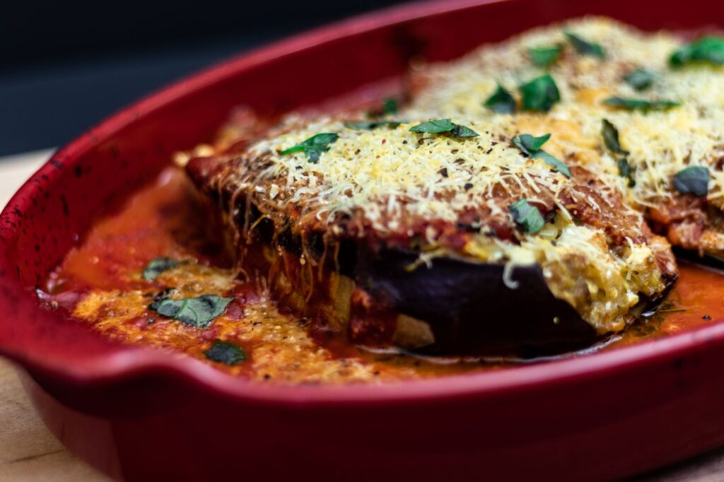 Délicieux plat de parmesan d'aubergine au four avec du fromage et de la sauce tomate dans un plateau rouge.