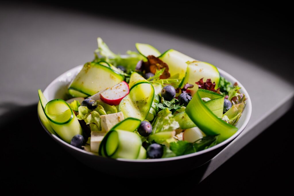 Délicieuse salade fraîche avec des rubans de courgette, radis, myrtilles et fromage feta, parfaite pour un repas sain.