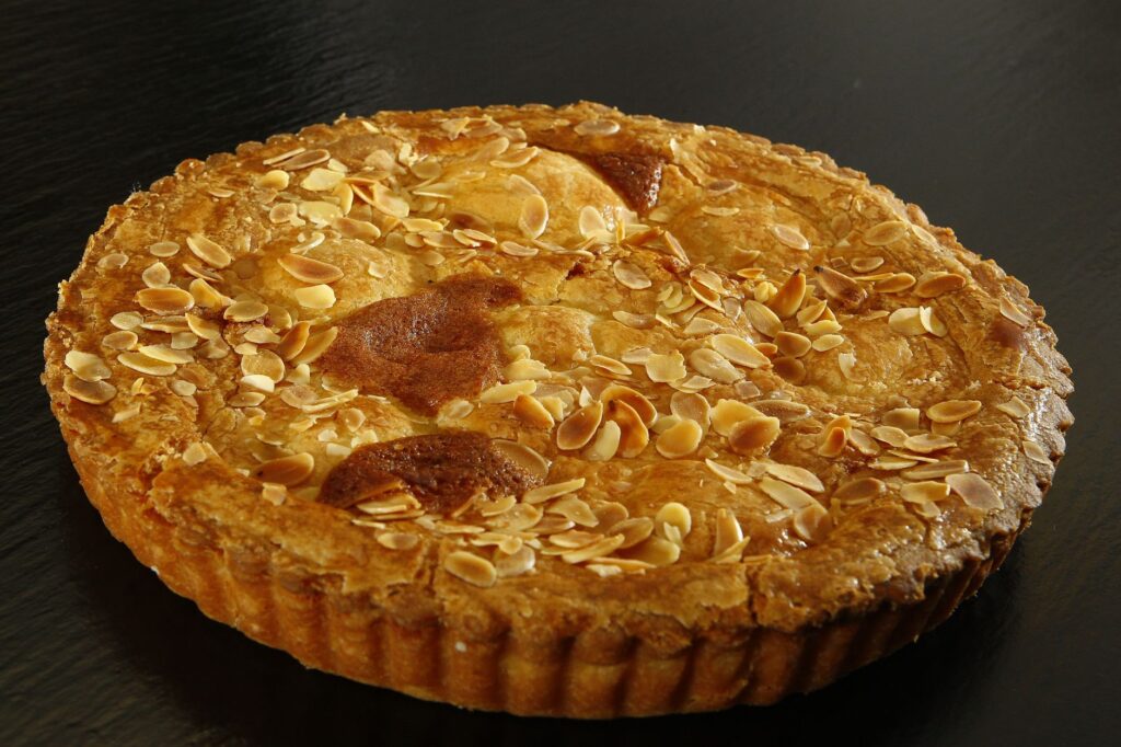 Délicieuse tarte aux amandes maison avec croûte dorée sur fond sombre.