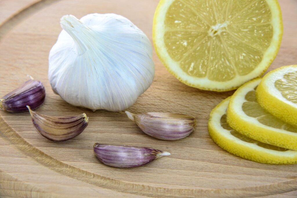 Gros plan sur de l'ail frais et des tranches de citron sur une planche en bois, idéal pour une cuisine saine.