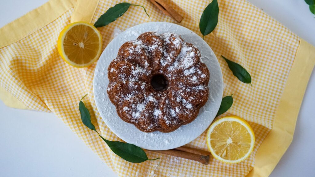 Délicieux gâteau bundt au citron fait maison avec un glaçage de sucre glace et des bâtons de cannelle.