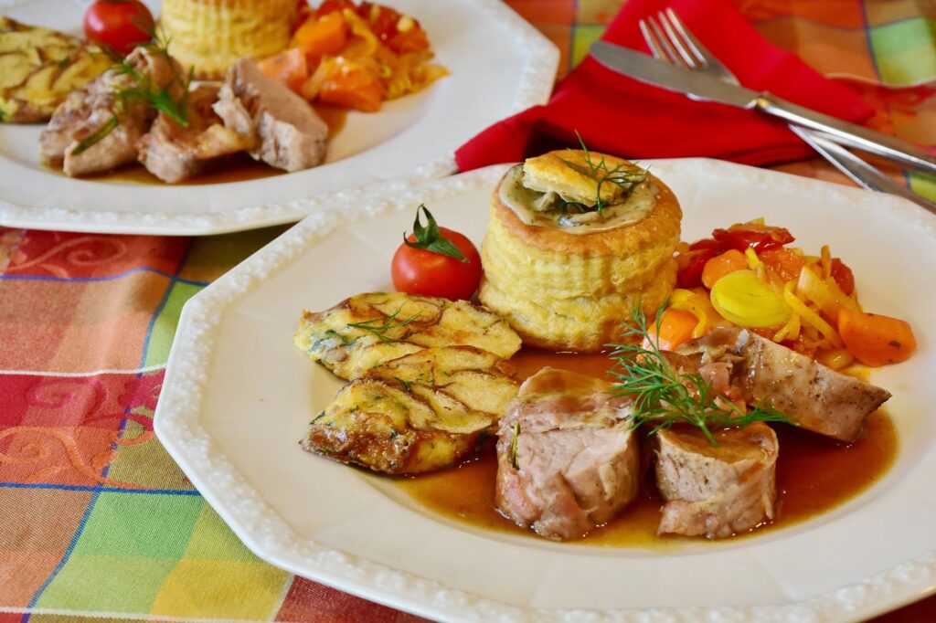 Élégant filet de porc avec des légumes, pâte feuilletée et garniture de tomate, parfait pour un repas gastronomique.