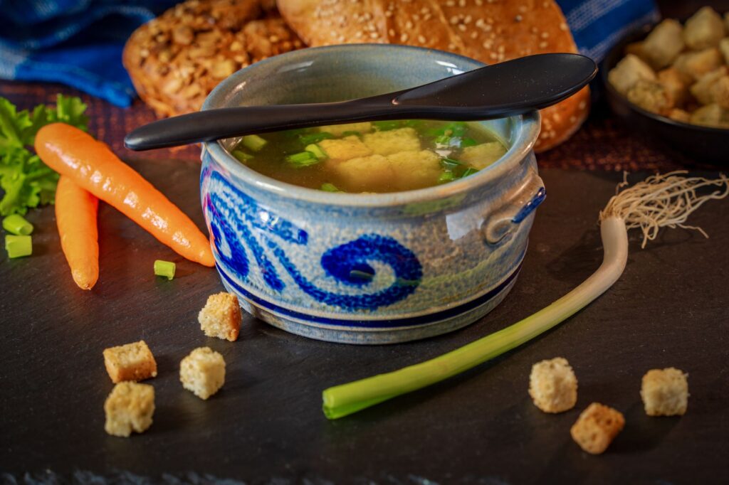 Un bol réconfortant de bouillon de légumes avec des carottes fraîches, des poireaux et des croûtons, parfait pour un repas douillet.