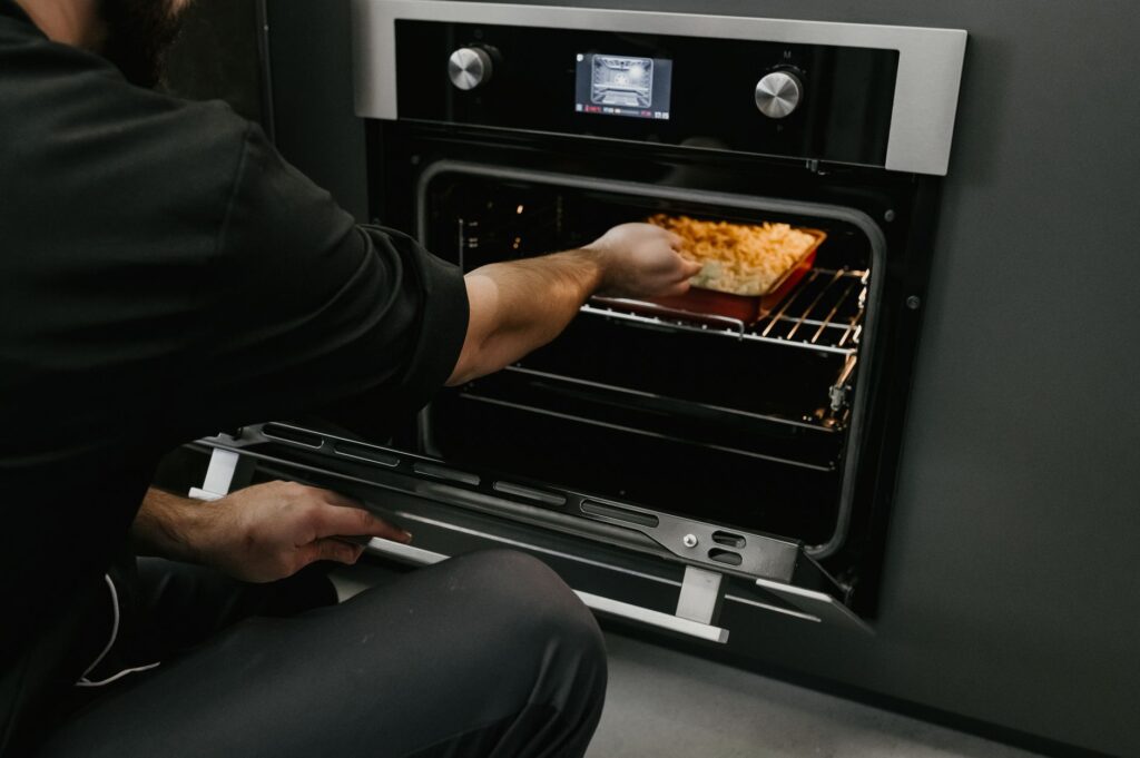 Un chef plaçant un gratin de pâtes dans un four dans une cuisine moderne.
