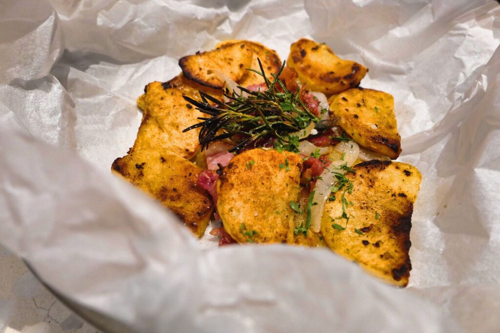 Délicieuses tranches de pommes de terre cuites au four de style rustique avec des herbes fraîches sur du papier sulfurisé.