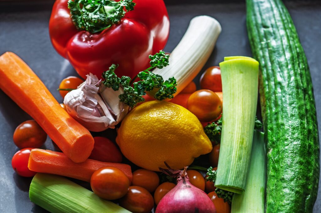 Une présentation plate et vibrante de légumes frais et d'ingrédients comprenant des poivrons, des poireaux et du citron.