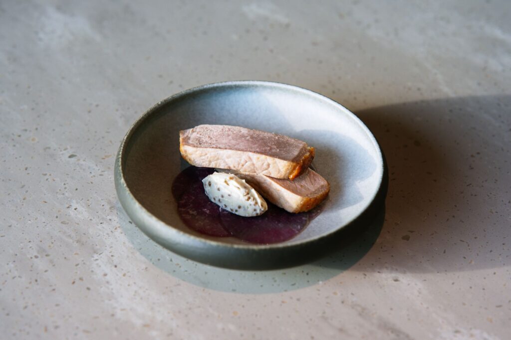 Présentation élégante de magret de canard en sauce sur une assiette moderne, mettant en valeur une cuisine raffinée.