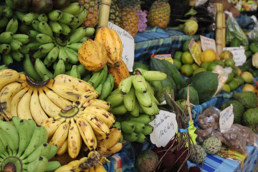 Assortiment dynamique de fruits tropicaux, notamment des bananes et des ananas, sur un marché en plein air.