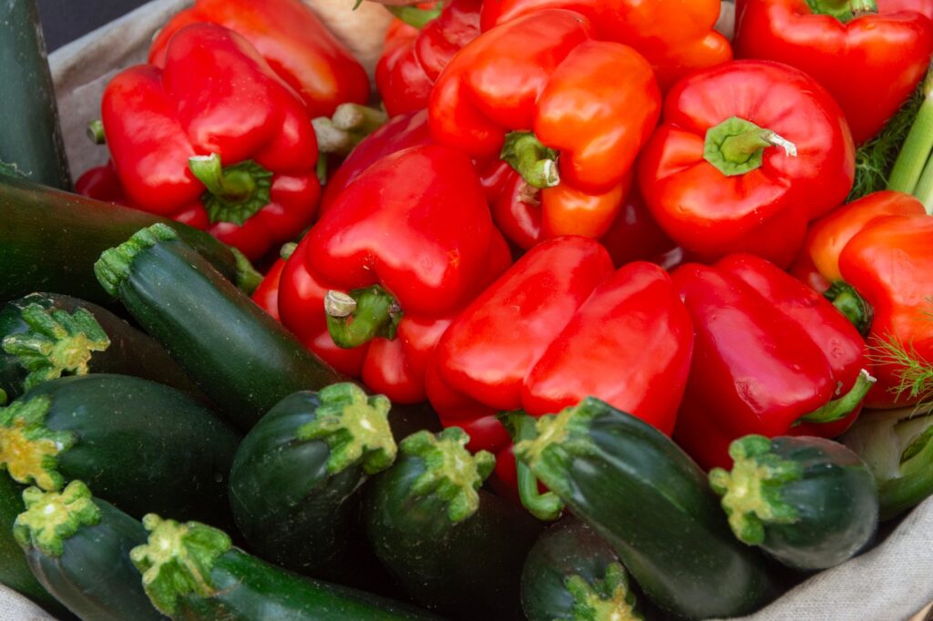 Un étalage vibrant de poivrons rouges et de courgettes frais, idéal pour une cuisine et des recettes saines.