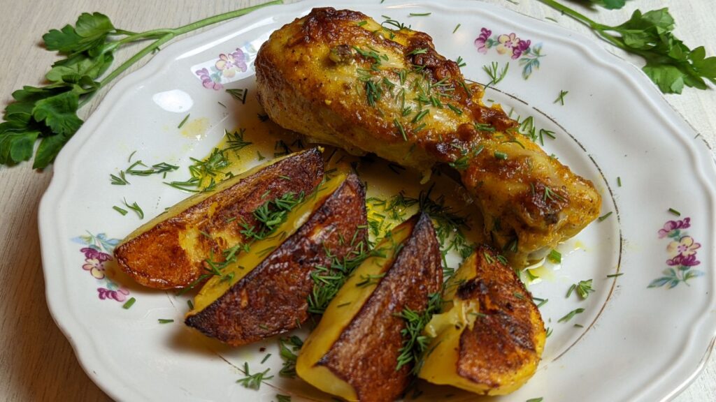 Délicieuse cuisse de poulet rôtie accompagnée de pommes de terre croustillantes garnies d'herbes fraîches sur une assiette fleurie.