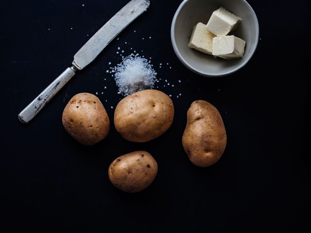Image à contraste élevé de pommes de terre, de beurre et de sel sur un fond sombre.