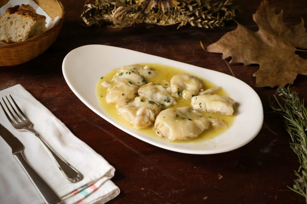 Assiette de filets de poisson nappés d'une riche sauce au beurre sur une table rustique.