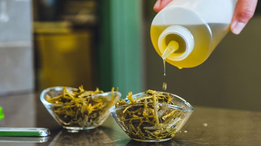 Verser de l'huile d'olive sur des herbes fraîches dans des bols en verre, ajoutant de la saveur au plat.