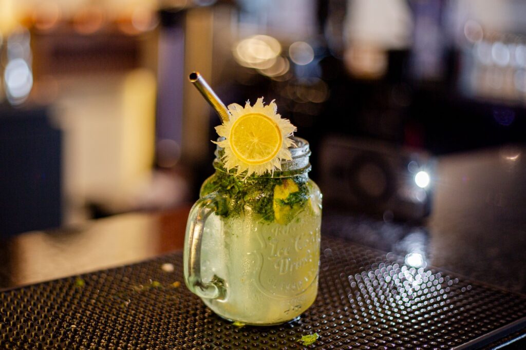 Un cocktail mojito vibrant dans un pot Mason, agrémenté de citron vert et de menthe. Idéal pour une boisson rafraîchissante.