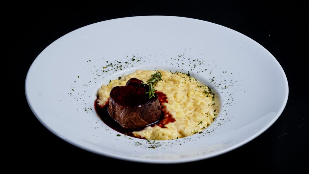 Délicieux filet de bœuf avec sauce au vin rouge et risotto crémeux garni d'herbes.