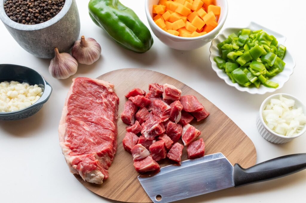 Un assortiment d'ingrédients frais, dont du bœuf, des légumes et des épices, prêts pour un ragoût maison.