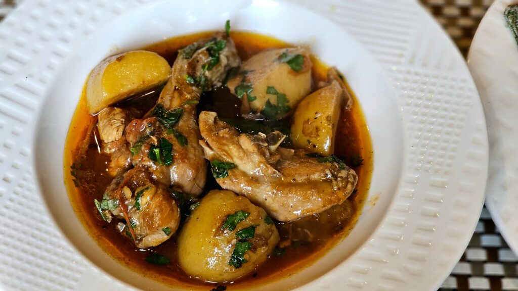 Délicieux ragoût de poulet aux pommes de terre, garni d'herbes fraîches, servi dans un plat blanc.