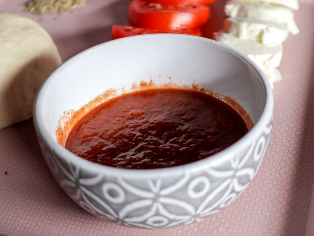 Un bol de sauce tomate entouré de mozzarella et de tranches de tomates, parfait pour la cuisine italienne.