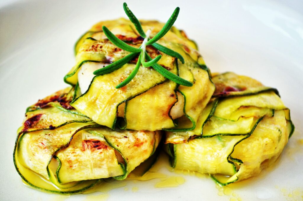 Délicieux wraps de courgettes farcis au poulet grillé, présentés avec une garniture de romarin frais.