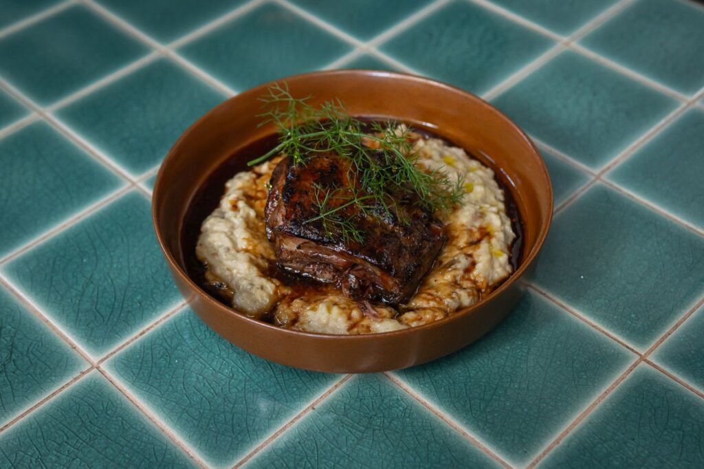 Gros plan sur un plat de bœuf gastronomique servi avec de la purée de pommes de terre dans une assiette élégante.