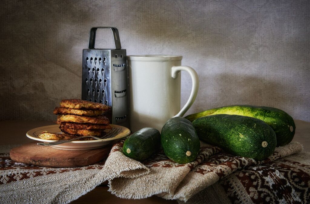 Composition artistique de courgettes, de crêpes et d'ustensiles de cuisine dans une nature morte rustique.