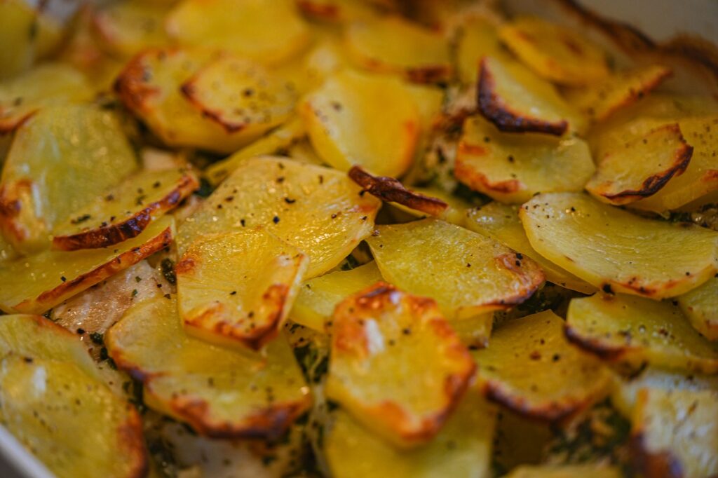 Tranches de pommes de terre rôties dorées assaisonnées d'herbes et de poivre, cuites à la perfection croustillante.