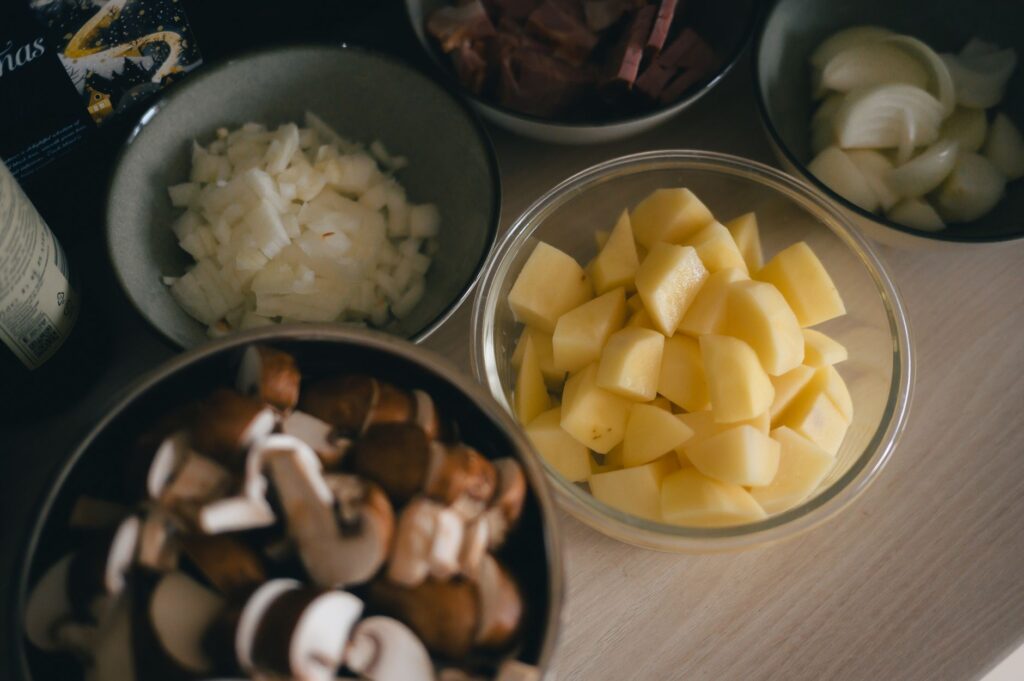Un assortiment de légumes et d'ingrédients coupés en dés, présentés dans des bols et prêts à être cuisinés.