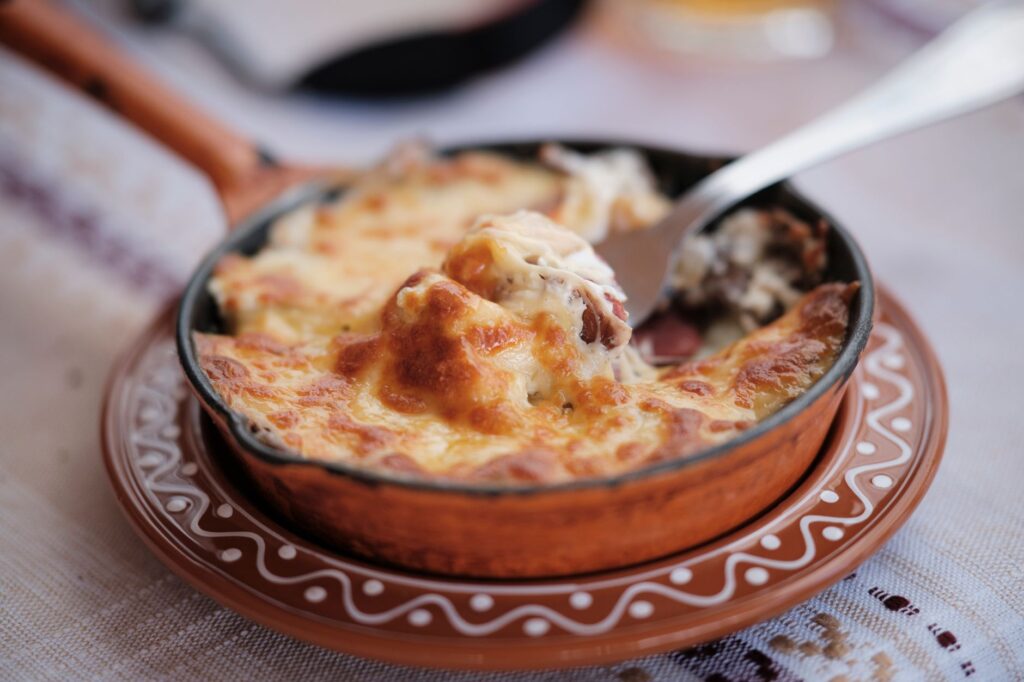 Un plat au fromage parfaitement cuit, servi dans un pot en céramique rustique avec une croûte dorée et croustillante.