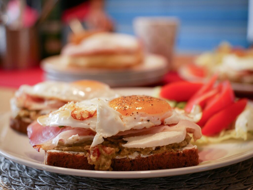 Gros plan sur un petit-déjeuner savoureux avec des œufs au plat, de l'avocat et du jambon sur du pain grillé.