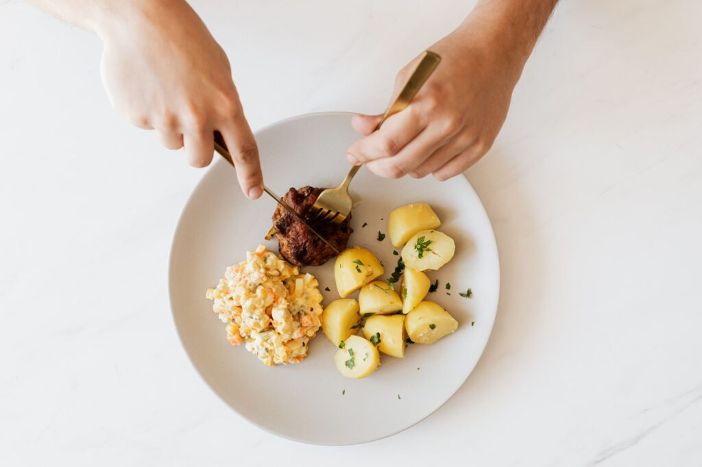 Vue aérienne d'une assiette avec de la viande, des pommes de terre et de la salade servie.