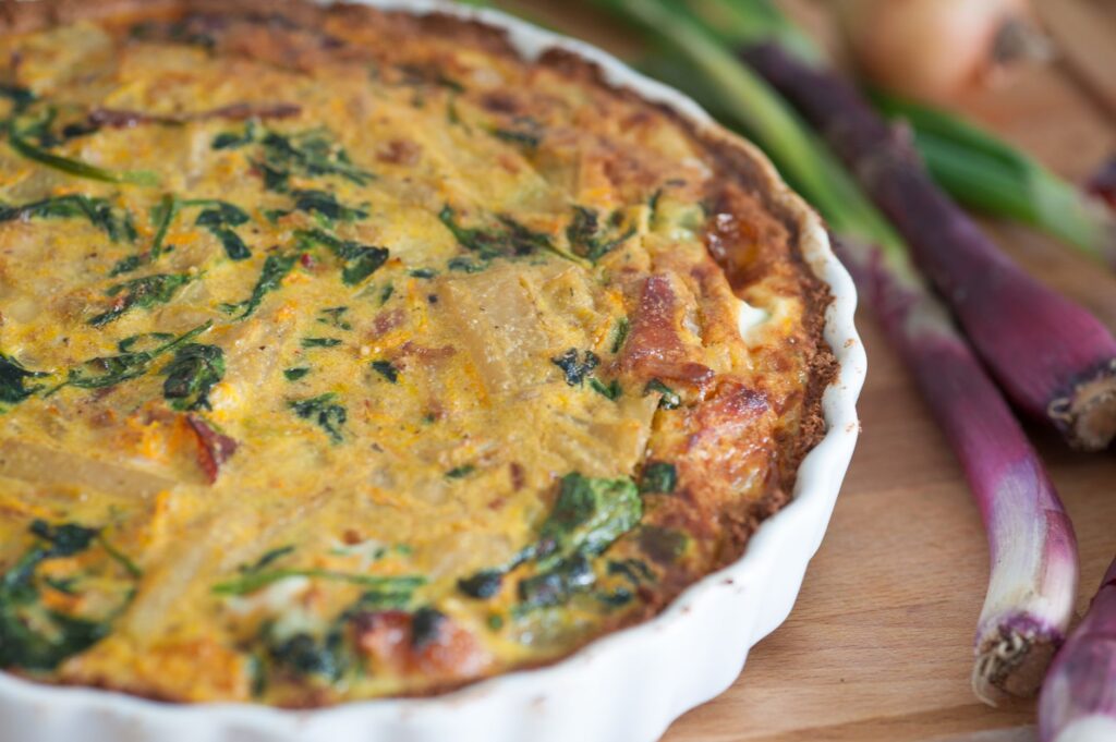 Délicieuse quiche maison avec des oignons rouges frais et des épinards, parfaite pour un repas savoureux.