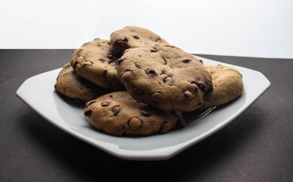 De somptueux cookies aux pépites de chocolat empilés sur une assiette blanche, prêts à être dégustés.