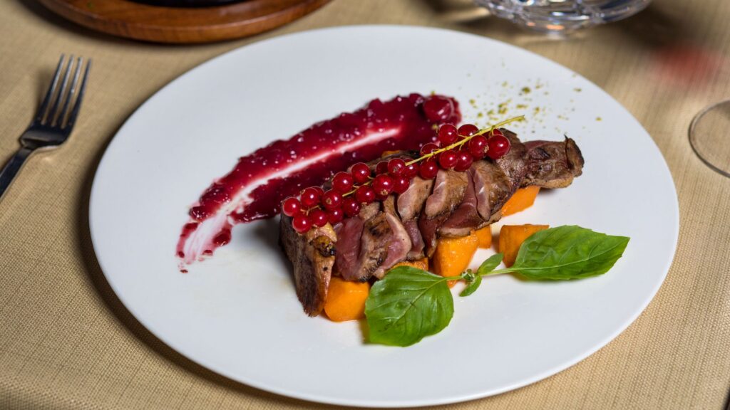 Magret de canard élégant avec sauce aux baies, garni d'herbes et de légumes, parfait pour un dîner gastronomique.