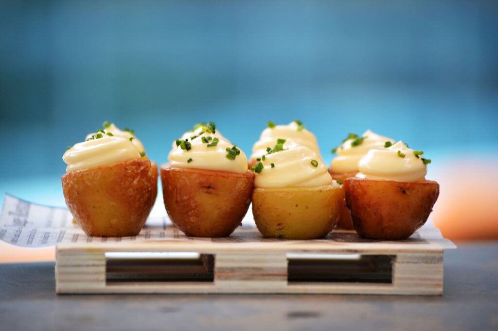 Délicieuses bouchées de pommes de terre haut de gamme garnies de crème et de ciboulette fraîche sur un plat en bois.