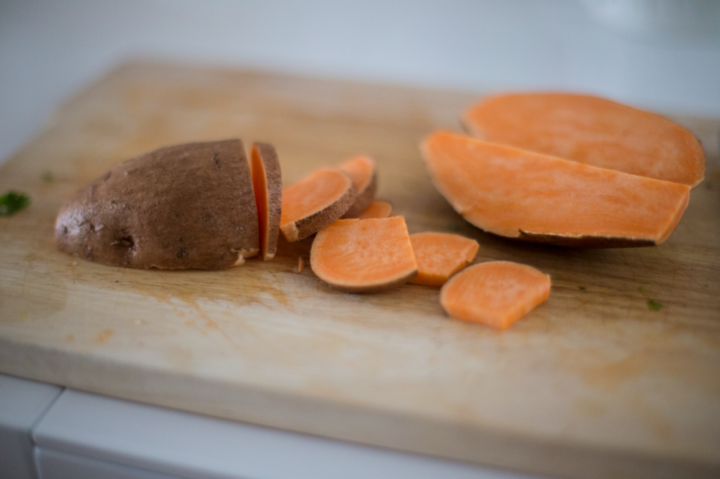 Gros plan de patate douce tranchée sur une planche à découper en bois, idéale pour s'inspirer en cuisine.