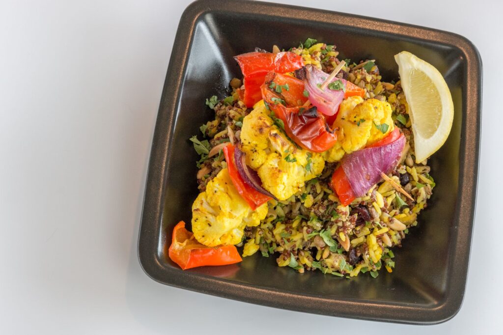 Plat coloré de riz de chou-fleur vegan avec des légumes frais et une tranche de citron.